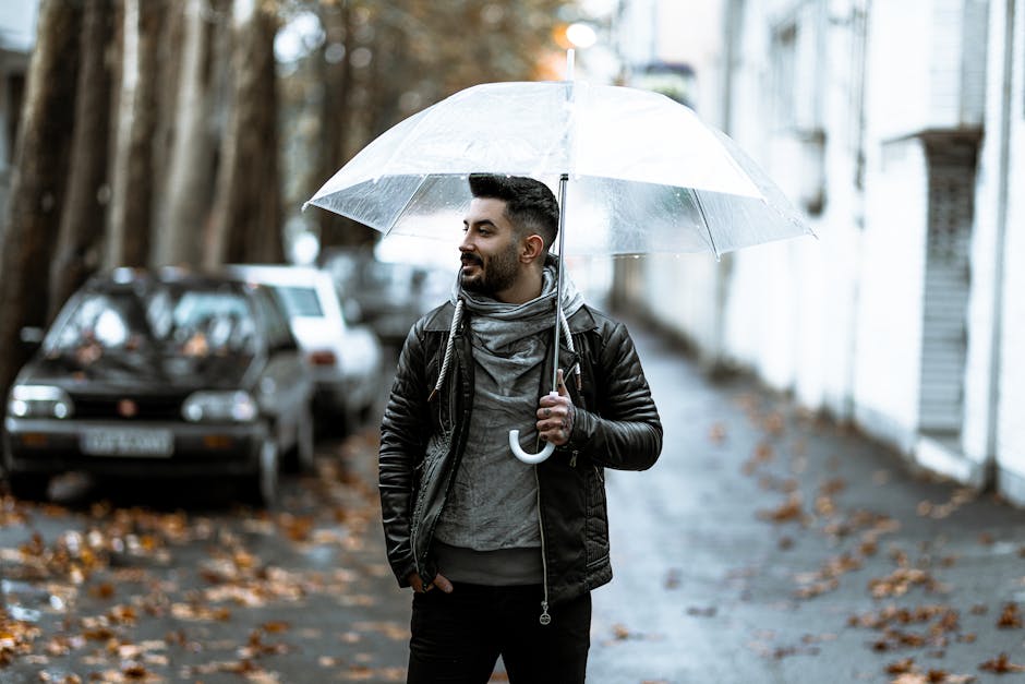 Confident man holding transparent umbrella on a rainy city street.